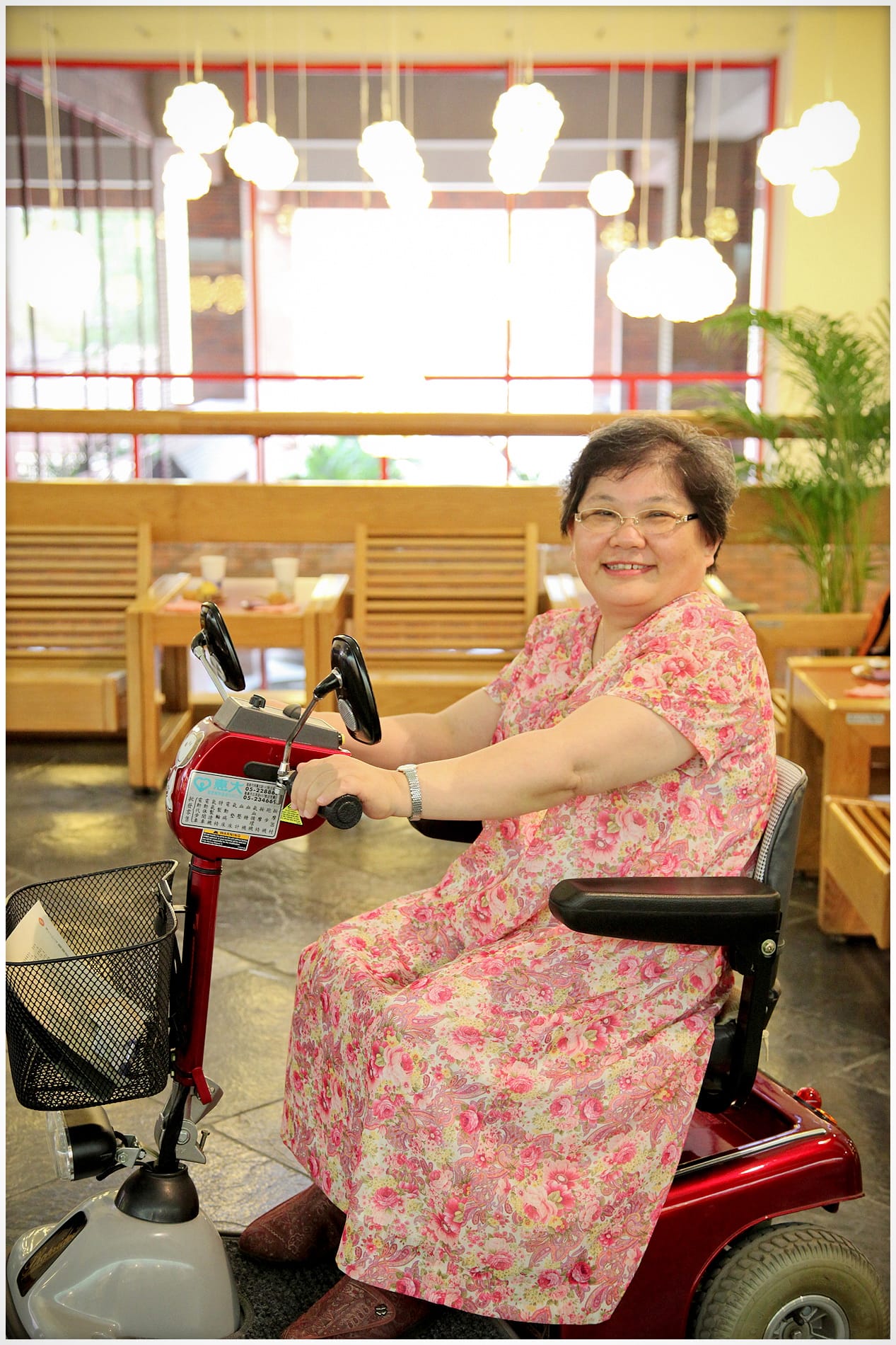 王國羽教授坐在紅色代步車上側身微笑